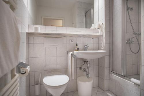 a white bathroom with a toilet and a sink at Trail Hotel Oberstaufen in Oberstaufen