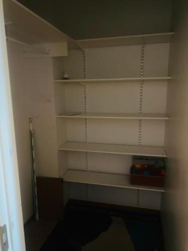 a closet with white shelves in a room at Jeffrey in Vantaa