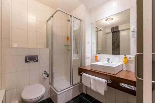 a bathroom with a shower and a toilet and a sink at Parkhotel Horst - Venlo in Horst