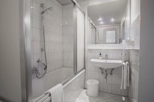 a white bathroom with a shower and a sink at Trail Hotel Oberstaufen in Oberstaufen