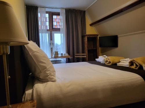 a hotel room with a bed and a window at Hotel Stedswal in Sloten