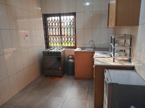 una piccola cucina con fornelli e finestra di Dawhenya Bungalow 2 a Tema