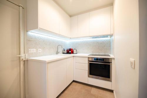 une cuisine blanche avec un évier et une cuisinière dans l'établissement Elegant apartment - 2BR - 6P - Notre Dame Cathedral, à Paris
