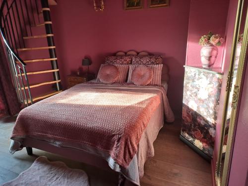 a bedroom with a bed with pink walls and a staircase at BOIS DE CHENES HOUSE in Phalsbourg