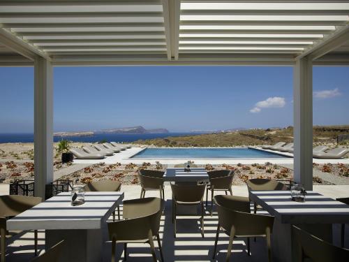 a restaurant with tables and chairs and a pool at Absolute Paradise Santorini in Akrotiri