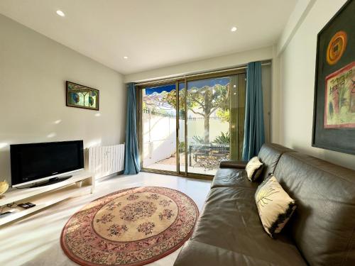 un salon avec un canapé et une grande fenêtre dans l'établissement Le Concorde By SCLS Locations, à Cannes