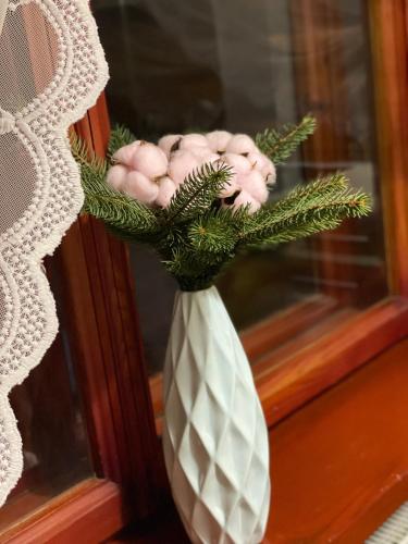 a white vase with a plant in a window at Еко котедж Яблуницька троянда in Yablunytsya