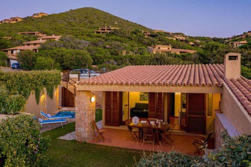 a house with a patio with a table in the yard at Villa Lumière in Costa Paradiso