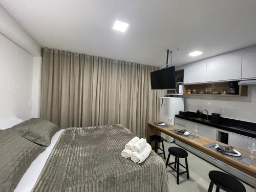 een slaapkamer met een bed en een bureau met een keuken bij RN Studio Premium 103 Vista Mar in Maceió
