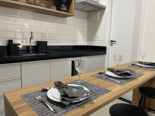 een keuken met een houten tafel met borden en glazen bij RN Studio Premium 103 Vista Mar in Maceió