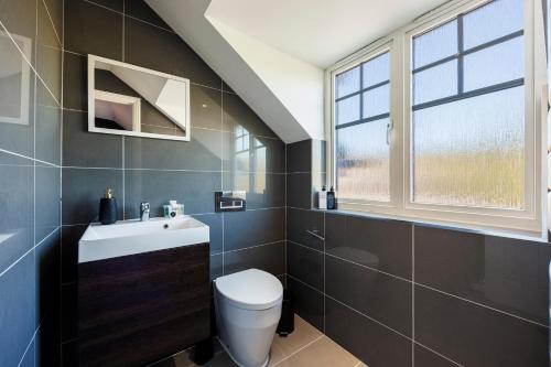 a bathroom with a toilet and a sink and a window at 4 Bed Townhouse in Uxbridge Ideal For Families or Contractors By AV Stays Short Lets in Hillingdon
