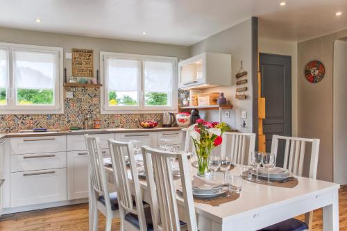une cuisine avec une table blanche et des chaises ainsi qu'une salle à manger dans l'établissement Les Bicoques à la mer - 