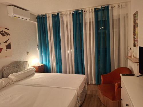 - une chambre avec un lit, une chaise et des rideaux bleus dans l'établissement Great Waterfront Apartment In Cannes BoccaCabana, à Cannes