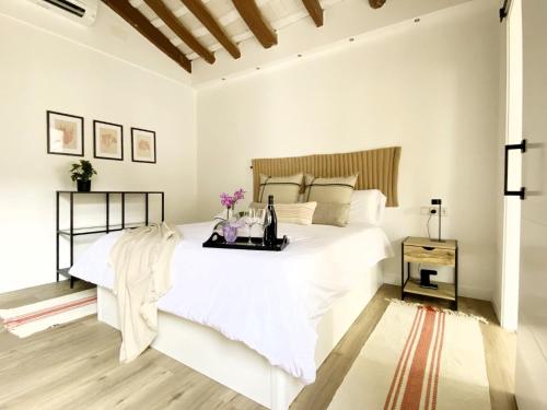 a white bedroom with a large bed with a tray on it at Historic House at Can Quintana by Casa de Elena in Pineda de Mar