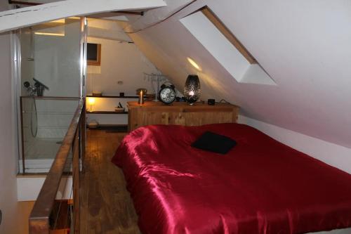 - une chambre mansardée avec un lit rouge dans l'établissement Love Loft et Spa, à Ancy-le-Franc