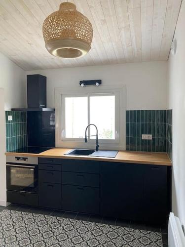 une cuisine avec un évier et une fenêtre dans l'établissement Maison située à 150m de la plage de la Madeleine, à Noirmoutier-en-l'lle