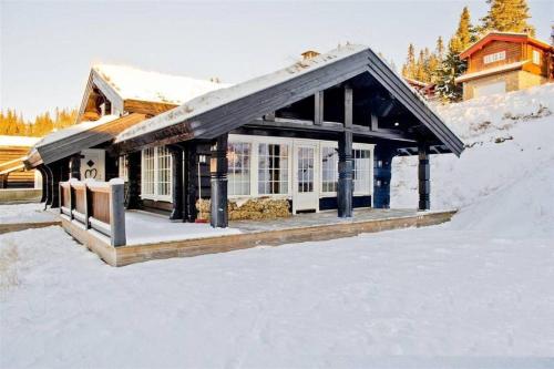 a small house in the snow with snow at Large family cabin in Hafjell ski in-out, BBQ, terrace and fireplace in Hafjell