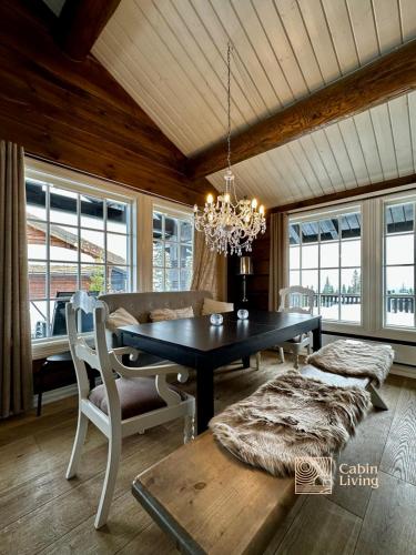 a dining room with a table and a couch and windows at Large family cabin in Hafjell ski in-out, BBQ, terrace and fireplace in Hafjell