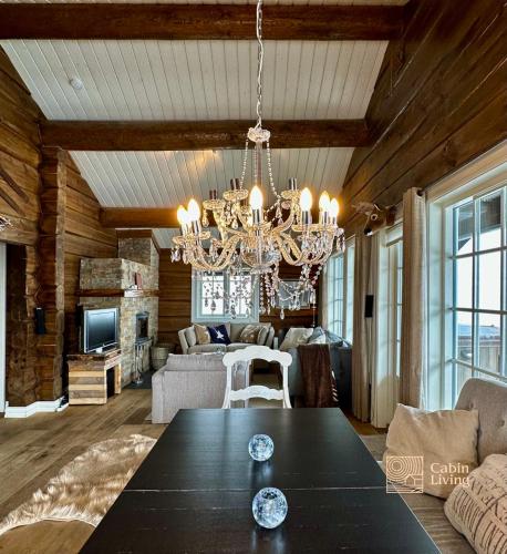 a living room with a table and a chandelier at Large family cabin in Hafjell ski in-out, BBQ, terrace and fireplace in Hafjell