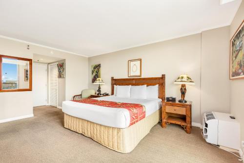 a hotel room with a large bed and a table at Luana Waikiki Hotel & Suites in Honolulu