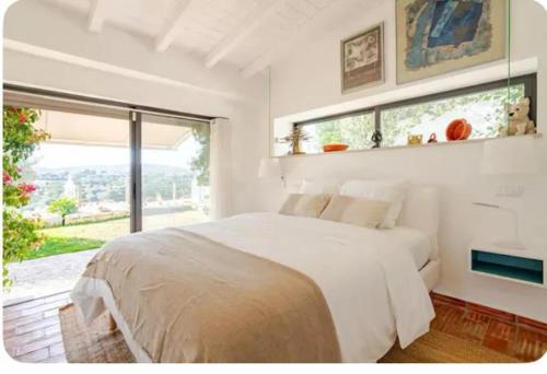 a white bedroom with a large bed and a window at Cozy house in São Brás de Alportel with shared pool 60 m² in São Brás de Alportel