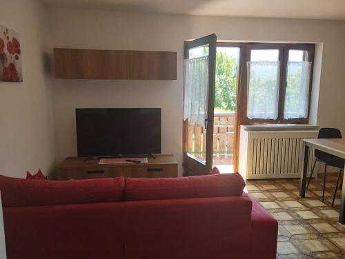 a living room with a red couch and a flat screen tv at Casa Erica - Carano in Carano