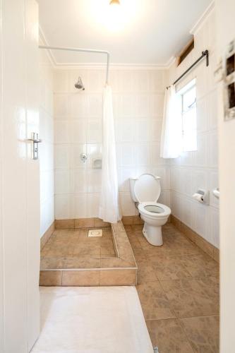 a white bathroom with a toilet and a shower at Masindi Hotel in Masindi