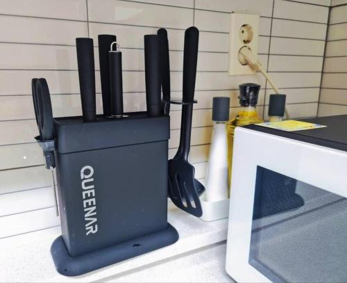 a container of knives on a counter next to a microwave at Seoul, 3 rooms, Gimpo Airport, free parking, 1 PM check-out, super close to the station, 10 people, warm accommodation, 4 beds, Hongdae, Jongno, Myeongdong in Seoul