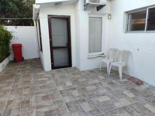 un patio con 2 sillas blancas y una puerta en Casa Amplia Avenida Solari, en La Paloma