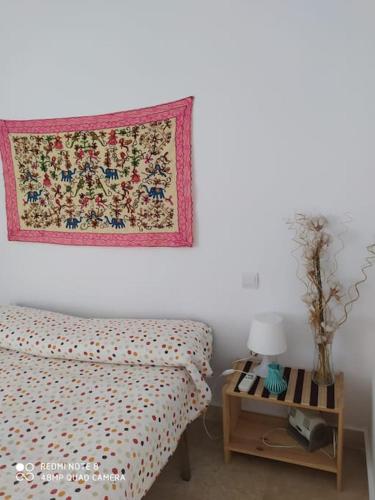 a bedroom with a bed and a table with a rug on the wall at Eli's Home in Málaga