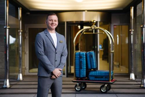 a man in a suit standing next to a cart at 30th+ Floor Apartments in Sky Tower in Wrocław