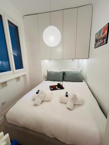 - une chambre avec un grand lit blanc et 3 serviettes dans l'établissement Appartement de Standing - Place des Vosges - Cozy 2 pieces - une chambre, à Paris