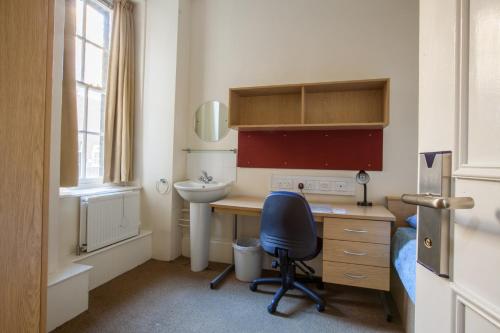 a bathroom with a sink, toilet, and chair at LSE Passfield Hall in London