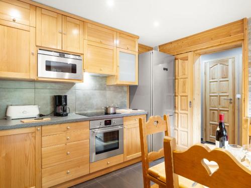 une cuisine avec des armoires en bois et des appareils en acier inoxydable dans l'établissement Apartment Le Petit Savoyard-5 by Interhome, à Châtel