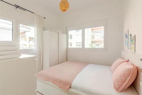 a white bedroom with a bed and two windows at Serenity Apartment in Perea