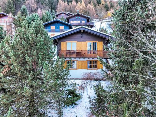a house with a balcony in the middle of trees at Chalet Magicien by Interhome in Nendaz