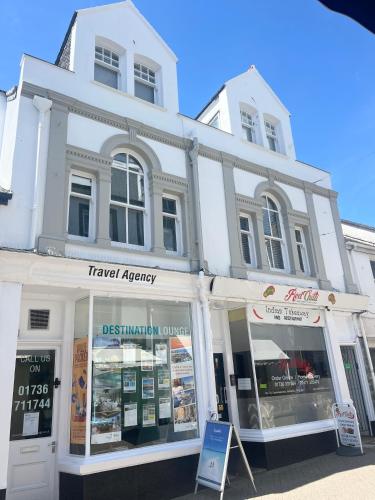 a white building with shops in front of it at Bright~ Town Center~ 2 bed~Penzance in Penzance