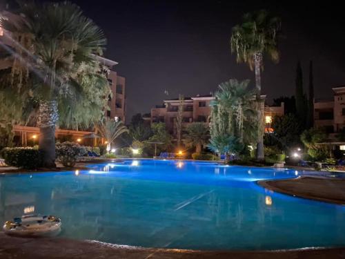 a large swimming pool with palm trees at night at Aphrodite gardens 2 bedroom in Paphos City