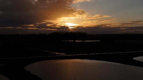 a sunset over a field with a body of water at Guesthouse De Wissen in Dilsen-Stokkem