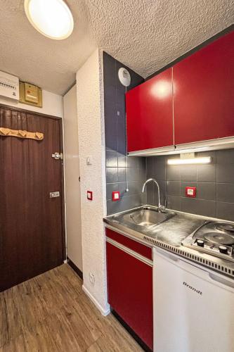 une cuisine avec des armoires rouges et un évier dans l'établissement Studio Les Tommeuses - Val Claret-25 by Interhome, à Tignes