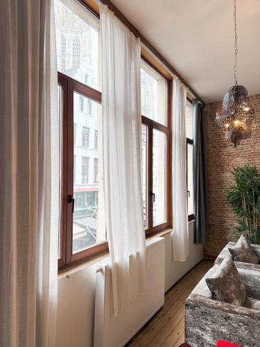 a room with windows and a couch and a chandelier at LouLou Home's in Antwerp