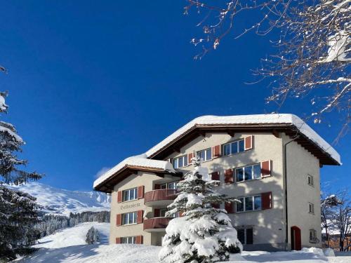 a building in the snow with a snow covered tree at Apartment Bellavista 6 by Interhome in Parpan
