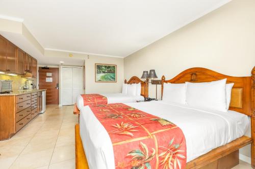a hotel room with two beds and a kitchen at Luana Waikiki Hotel & Suites in Honolulu