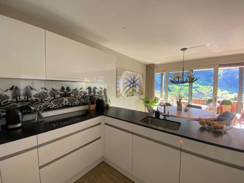 a kitchen with white cabinets and a black counter top at Apartment Alpenrose by Interhome in Adelboden