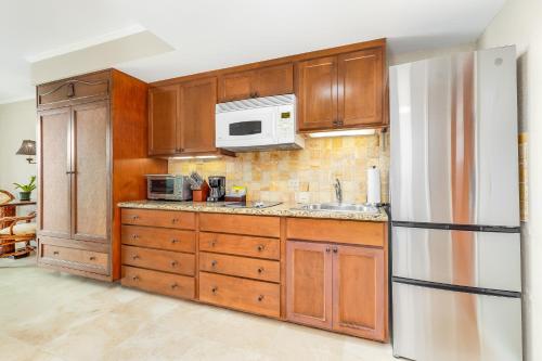 a kitchen with wooden cabinets and a white refrigerator at Luana Waikiki Hotel & Suites in Honolulu