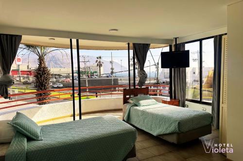 イキケにあるHotel Violeta Iquiqueのベッド2台とバルコニー付きのホテルの部屋
