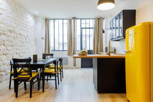 une cuisine et une salle à manger avec une table et des chaises noires dans l'établissement Loft Épuré et Confortable - 6 Pers Voltaire - 11e, à Paris