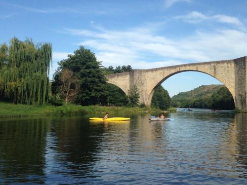 three people in kayaks on the water under a bridge at Apartment Les Vans-Cottage 3 pièces 6 personnes by Interhome in Chambonas