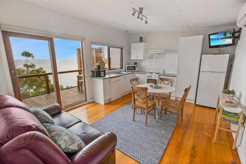 a living room with a couch and a kitchen with a table at Lakescapes Cottage in Metung