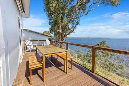 a wooden balcony with a wooden table and chairs on it at Lakescapes Cottage in Metung